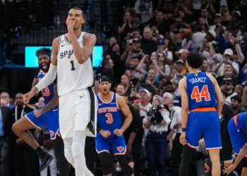 Victor Wembanyama of the San Antonio Spurs walks off the court while New York Knicks players Landry Shamet, Josh Hart, and Mitchell Robinson celebrate during Game 2 of the NBA Finals.