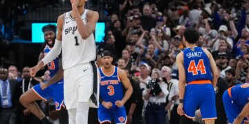 Victor Wembanyama of the San Antonio Spurs walks off the court while New York Knicks players Landry Shamet, Josh Hart, and Mitchell Robinson celebrate during Game 2 of the NBA Finals.