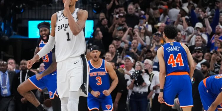 Victor Wembanyama of the San Antonio Spurs walks off the court while New York Knicks players Landry Shamet, Josh Hart, and Mitchell Robinson celebrate during Game 2 of the NBA Finals.
