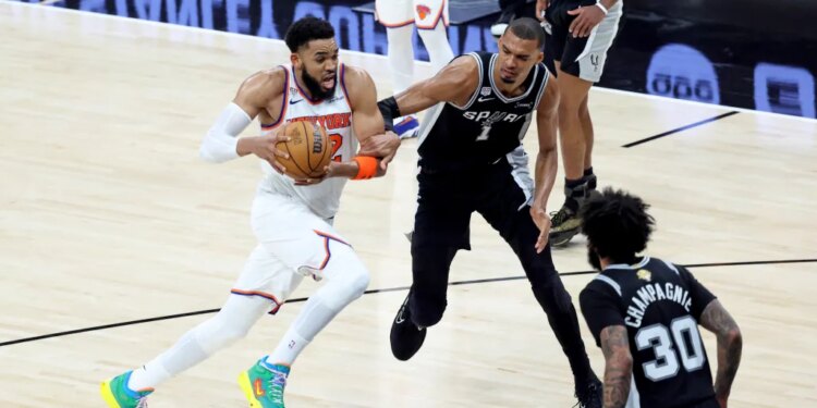 New York Knicks center Karl-Anthony Towns drives down court as San Antonio Spurs forward Victor Wembanyama gives chase during Game 1 of the NBA Finals.