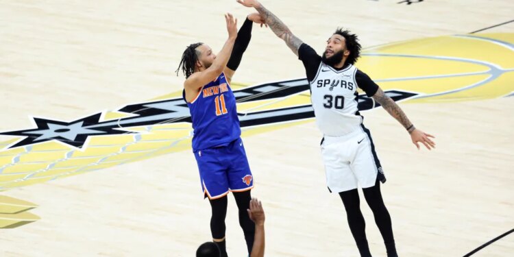 New York Knicks guard Jalen Brunson #11 hits a three-point shot over San Antonio Spurs forward Julian Champagnie #30 during the 1st half.
