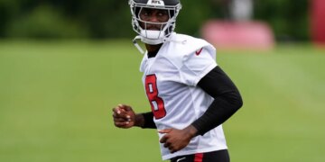 Kyle Pitts in a white jersey with a black helmet and number 8, looking to his right.