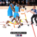 Basketball players in blue and white jerseys in an altercation, with a referee trying to intervene.