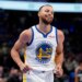 Stephen Curry smiling and wearing his Golden State Warriors jersey during a basketball game.