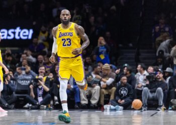 LeBron James wearing a yellow Los Angeles Lakers jersey with "23" on it, running on a basketball court.