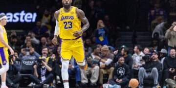 LeBron James wearing a yellow Los Angeles Lakers jersey with "23" on it, running on a basketball court.