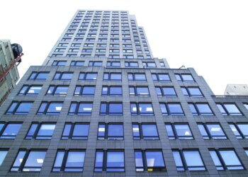 A low-angle view of 667 Madison Avenue & 61st Street, a tall building with many reflective windows.