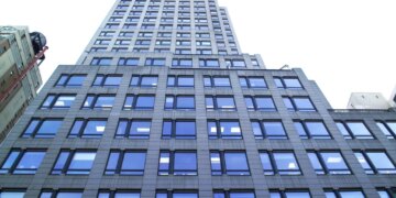 A low-angle view of 667 Madison Avenue & 61st Street, a tall building with many reflective windows.