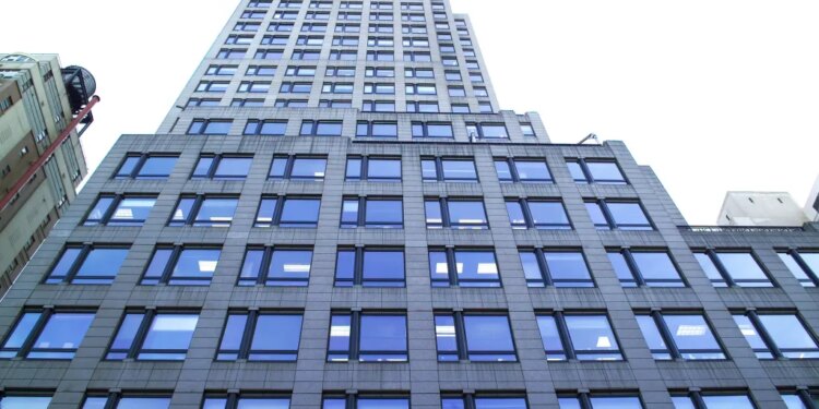 A low-angle view of 667 Madison Avenue & 61st Street, a tall building with many reflective windows.