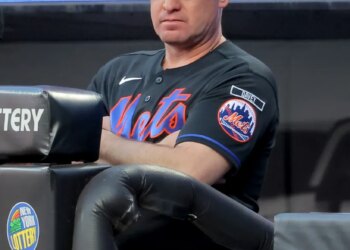 New York Mets manager Carlos Mendoza watching from the dugout.