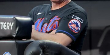 New York Mets manager Carlos Mendoza watching from the dugout.