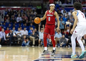 A Louisville player in a red jersey and a SMU player in a white jersey on the basketball court.