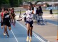 Track athlete Nyan Brown raising his hand in celebration as he crosses the finish line, costing his team a championship due to the gesture.