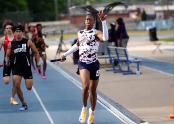 Track athlete Nyan Brown raising his hand in celebration as he crosses the finish line, costing his team a championship due to the gesture.