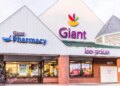 Exterior facade of a Giant grocery store and pharmacy, with "low prices" and promotional signs for ham, chicken, and shrimp visible through the windows.