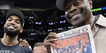 A smiling Patrick Ewing celebrates with Karl-Anthony Towns and a copy of the New York Post front page after the Knicks' 94-90 NBA title-clinching Game 5 win over the Spurs on July 13, 2026 in San Antonio.