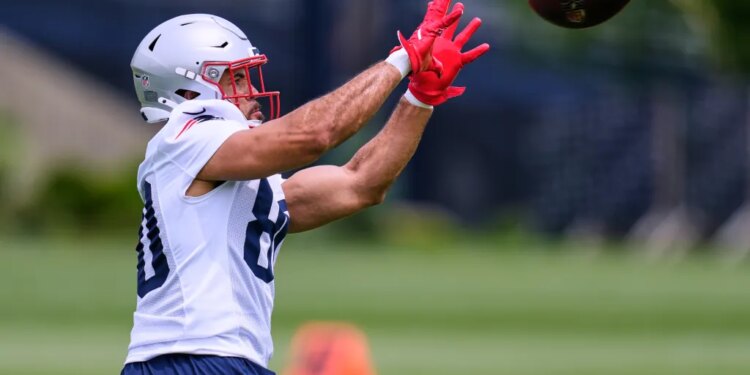 Julian Hill, wearing a white jersey and red gloves, catching a football during practice.