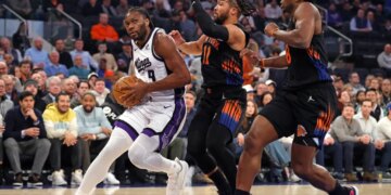 Sacramento Kings player Precious Achiuwa drives to the basket as New York Knicks players Jalen Brunson and OG Anunoby give chase.