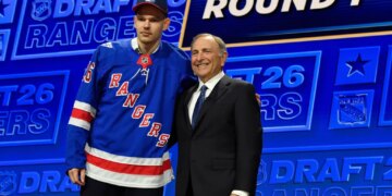 Alberts Smits, left, wearing a blue New York Rangers jersey, stands with NHL Commissioner Gary Bettman, right, at the NHL draft.