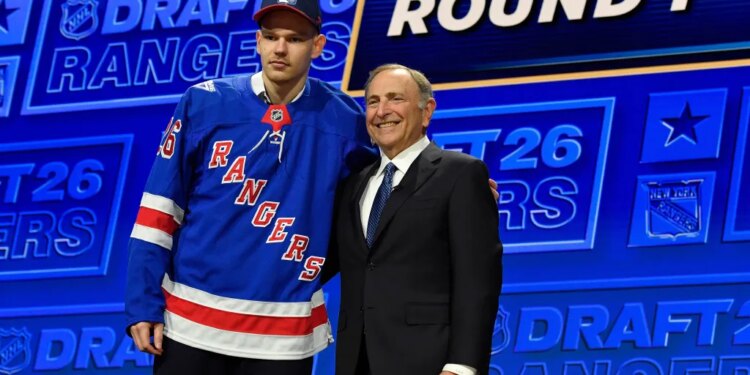 Alberts Smits, left, wearing a blue New York Rangers jersey, stands with NHL Commissioner Gary Bettman, right, at the NHL draft.