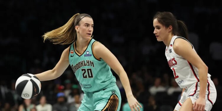 New York Liberty guard Sabrina Ionescu dribbling the ball while defended by Washington Mystics guard Sonia Citron.