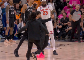 Victor Wembanyama and Mitchell Robinson watch as a fan runs onto the court.