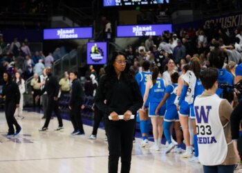 Shannon LeBeauf standing on a basketball court with a team of players.