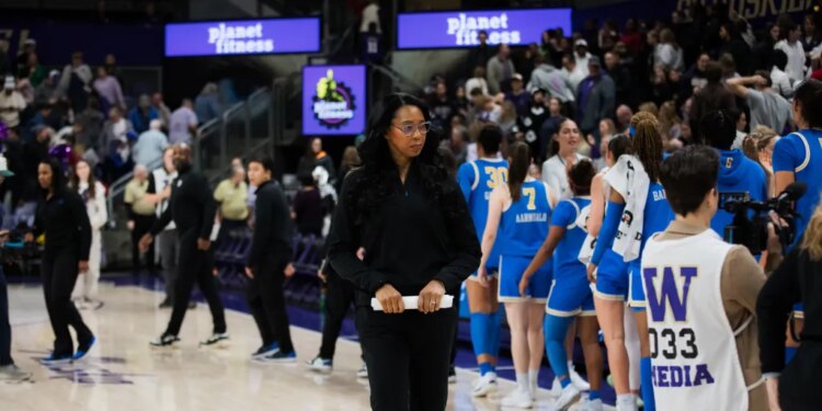 Shannon LeBeauf standing on a basketball court with a team of players.