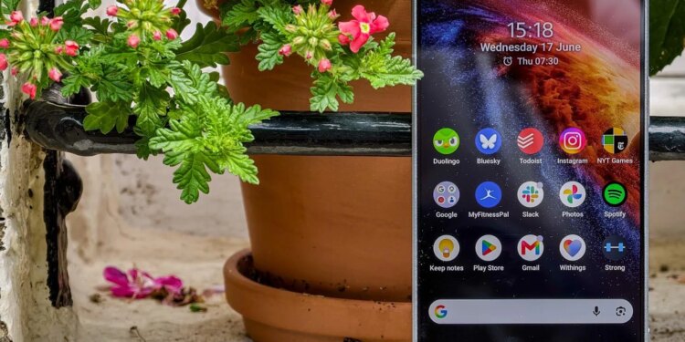 Photo of the Sony Xperia 1 VIII sitting on a windowsill in front of flowers, showing the home screen