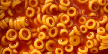 Close-up overhead view of Spaghettio's, a canned pasta consisting of ring-shaped pasta in tomato sauce.