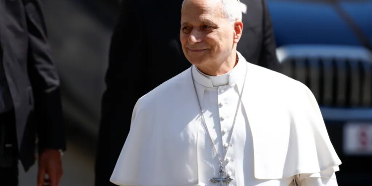 Pope Leo XIV smiling, wearing white papal attire and a silver crucifix.