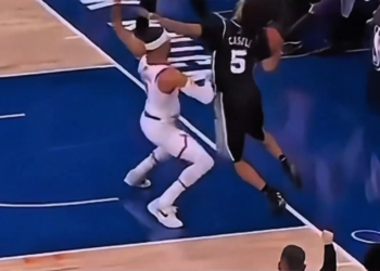 Two basketball players contesting a ball with one player's foot clearly out of bounds.