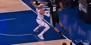 Two basketball players contesting a ball with one player's foot clearly out of bounds.