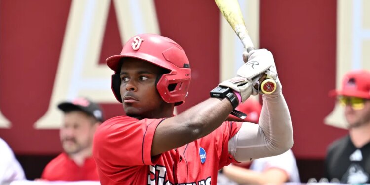 A baseball player in a red helmet and "St. John's" jersey holding a bat.