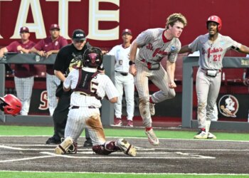 A St. John's baseball player in mid-air, having just scored a run.