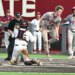 A St. John's baseball player in a gray striped uniform leaps over a Florida State catcher.