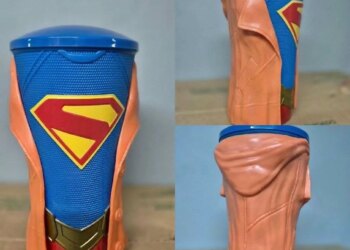 A Supergirl movie drink cup with a blue cup, Superman logo, gold belt buckle, and orange jacket.