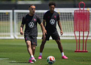 Sergino Dest and Tyler Adams on a soccer field.