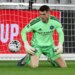 New York City FC goalkeeper Matt Freese in a lime green uniform, kneeling on the grass with a soccer ball to his left.