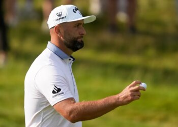 Jon Rahm holding a golf ball.
