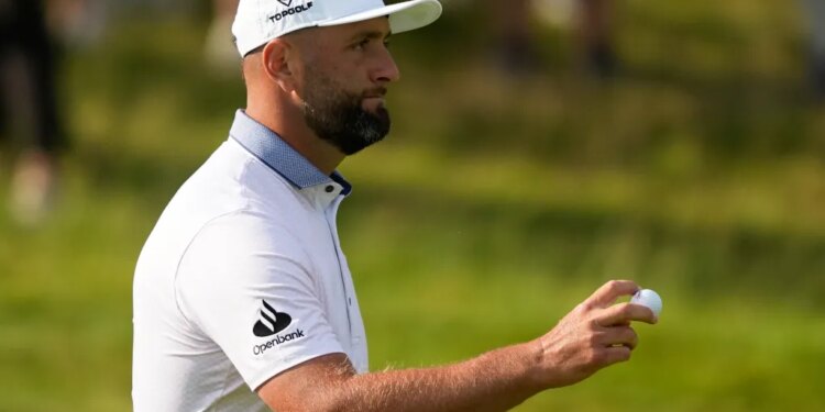 Jon Rahm holding a golf ball.