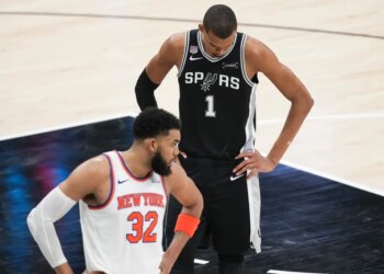 Victor Wembanyama looks down as Karl-Anthony Towns looks towards his bench during the NBA Finals.