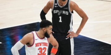 Victor Wembanyama looks down as Karl-Anthony Towns looks towards his bench during the NBA Finals.
