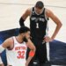 Victor Wembanyama looks down as Karl-Anthony Towns looks towards his bench during the NBA Finals.