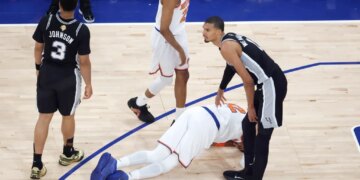 New York Knicks player Karl-Anthony Towns (32) lays on the floor after being fouled by San Antonio Spurs player Victor Wembanyama (1) during the third quarter of Game 4 of the 2026 NBA Finals.