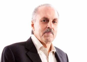 Photo of a man with gray hair and mustache, wearing a suit jacket and collared shirt.