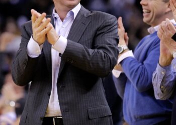 Warriors owner Joe Lacob clapping and smiling, with general manager Mike Dunleavy Jr. laughing next to him.
