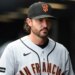 A San Francisco Giants player in a grey jersey and black cap looks off to his right.