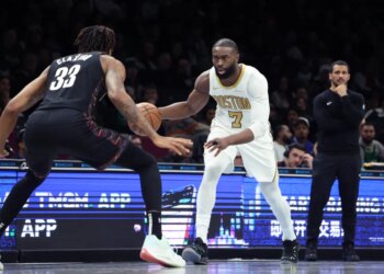 Boston Celtics guard Jaylen Brown dribbling the ball while guarded by Brooklyn Nets center Nic Claxton.
