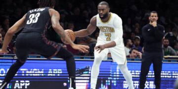 Boston Celtics guard Jaylen Brown dribbling the ball while guarded by Brooklyn Nets center Nic Claxton.